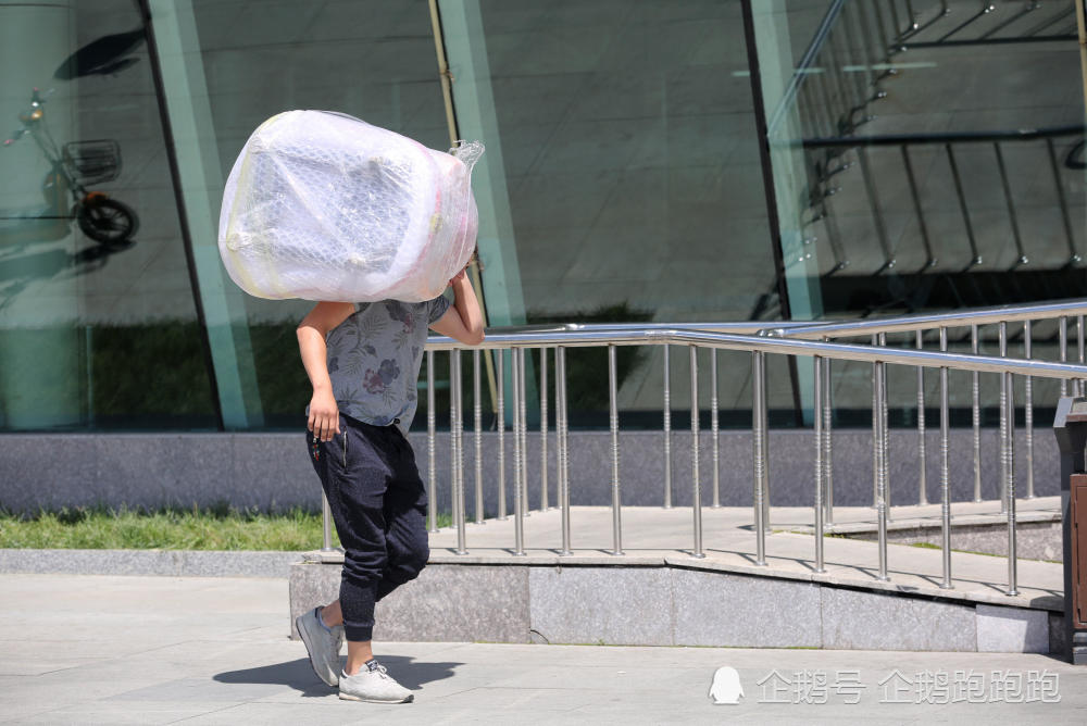 由于扛的东西太重了,一名年轻的俄罗斯"倒爷"在高温下,努力的坚持着.