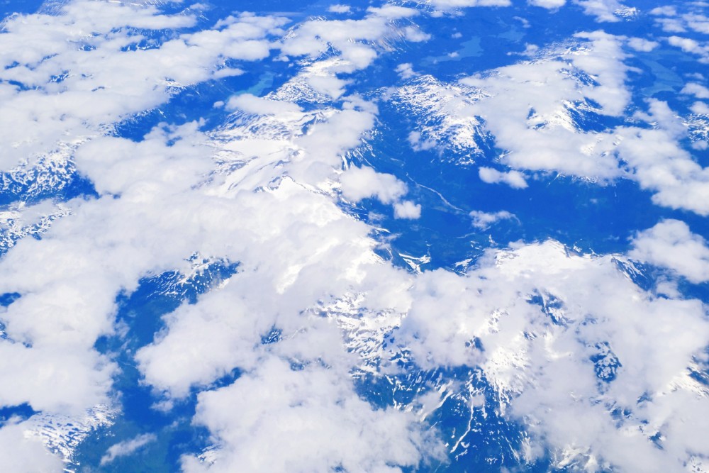 万米高空上航拍的美景,蓝天白云和若隐若现的雪山相映成画,这是在