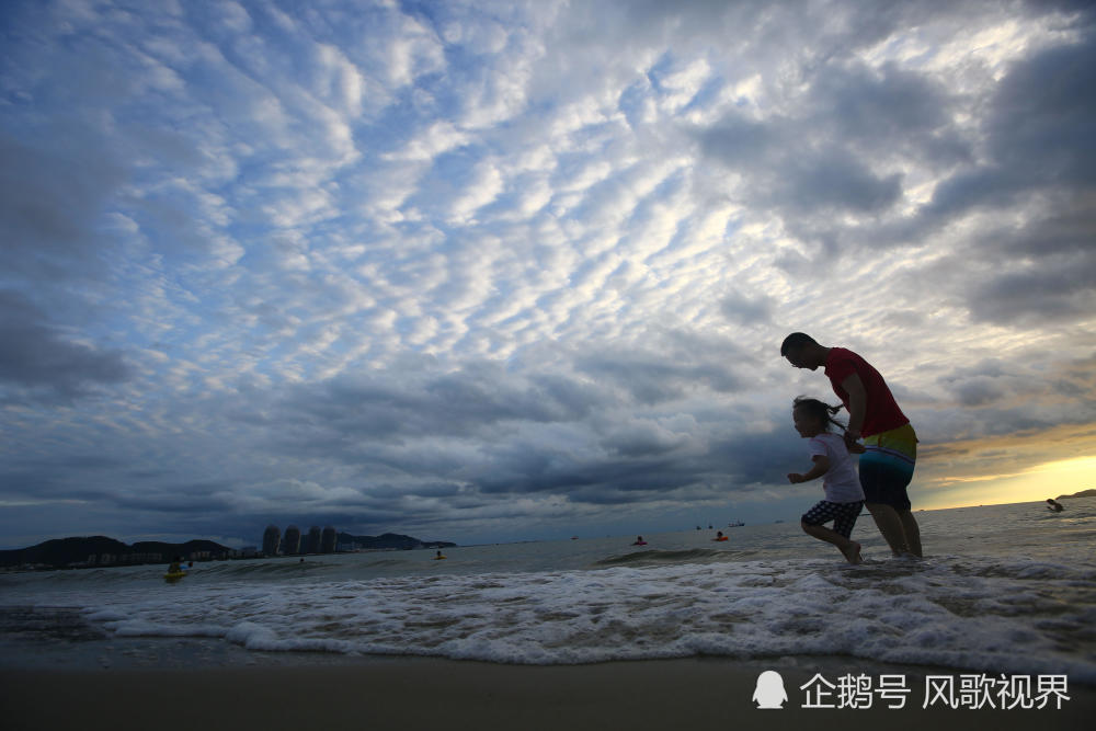 家长带孩子在三亚湾海边戏水.