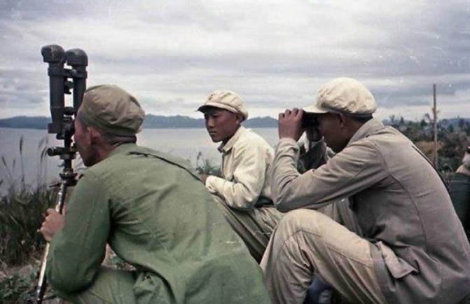 炮兵指挥官通过炮队镜和望远镜观察对岸的敌情.