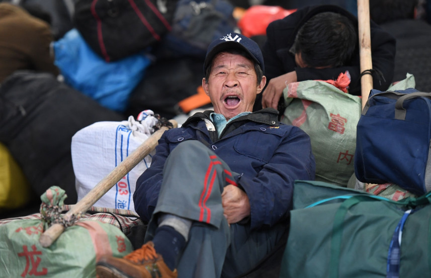 一位老年农民工躺在一堆行李中,候车的时间太长,老人打起了呵欠.