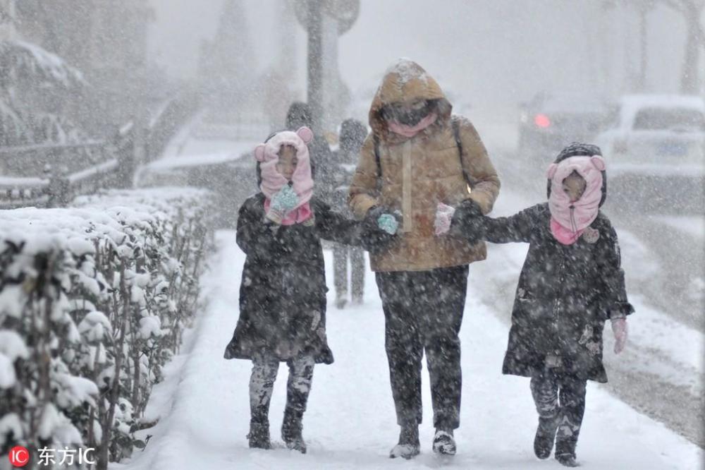 2018年12月7日,寒风呼啸,在山东威海菊花顶路,市民裹紧棉袄冒雪出行.