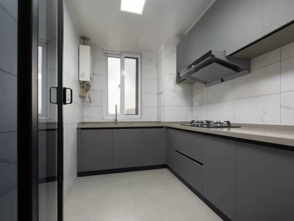 厨房整体选用灰色定制橱柜,配合大理石纹理墙砖,强化简约质感,橱柜的