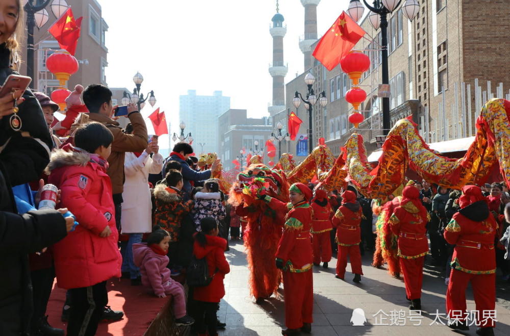 众多游客拍摄纪录了国际大巴扎步行街舞龙耍狮贺新春表演的热闹场景.
