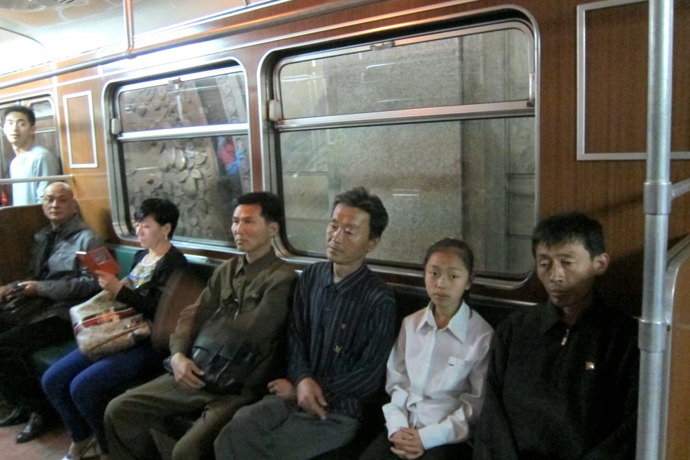 图为平壤地铁上乘客的表情,众人的表情都很冷漠,一名女子拿着手机在看