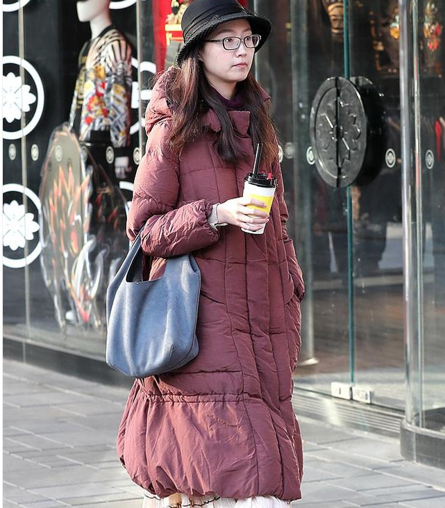 她穿一袭粉白色的多层叠荷叶边曳地长裙,外套一件干玫瑰色的棉质大衣.