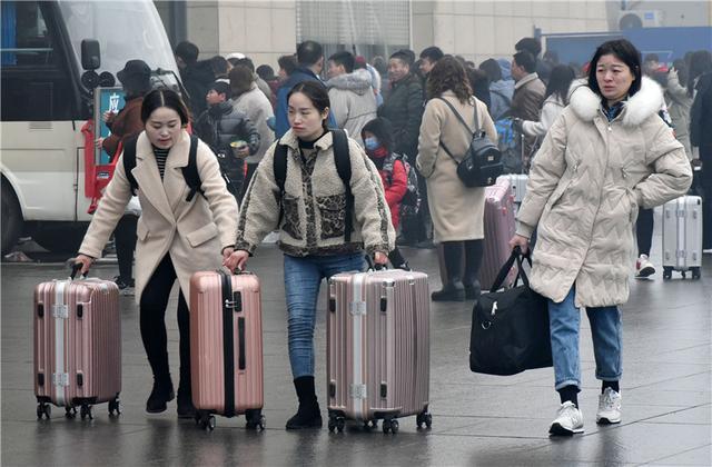 2月20日,旅客推着旅行箱走过河北邯郸火车站站前广场.