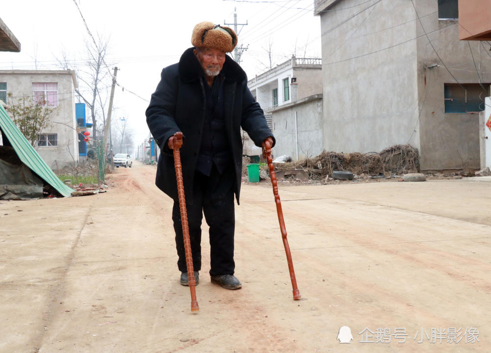 胡长山老人吃过饭后,拄着拐杖在自家门前的路上散步.