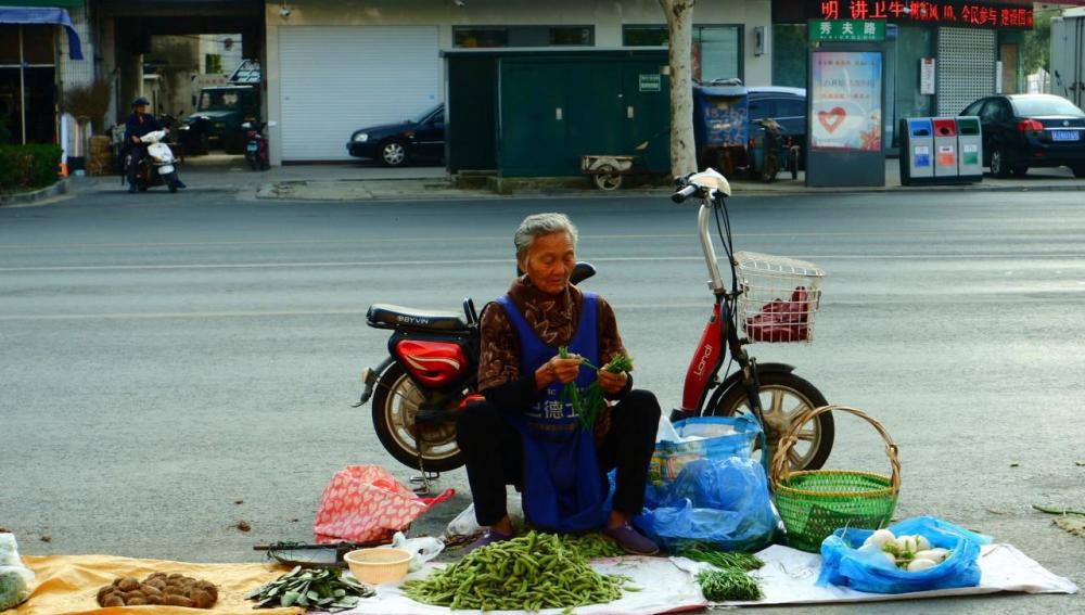 街边菜市场,大爷大妈在卖菜,挣钱不易,就怕城管