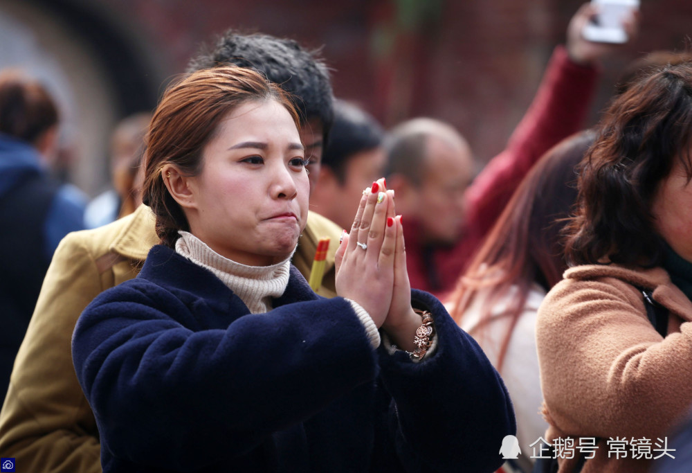 一位双手合十祈福的女孩,表情格外认真.