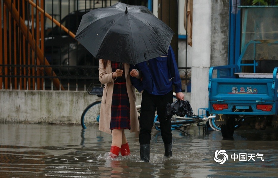 图为南昌市金鹰路积水严重,一对情侣撑伞蹚过积水路段.