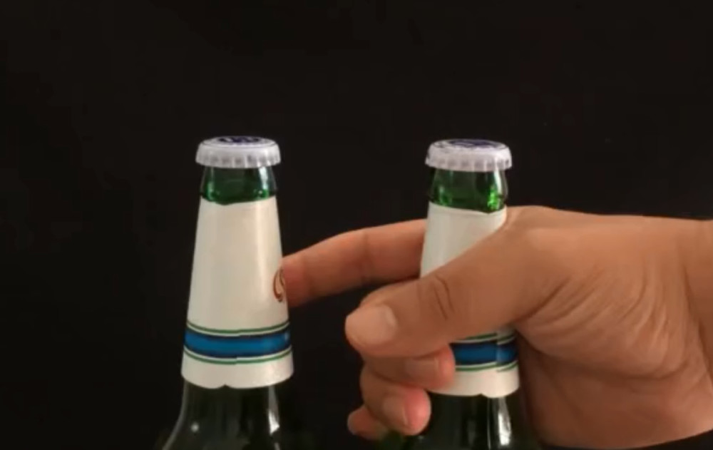 首先我们将其中的一瓶啤酒放在桌子上,然后再将另一瓶啤酒放在他的