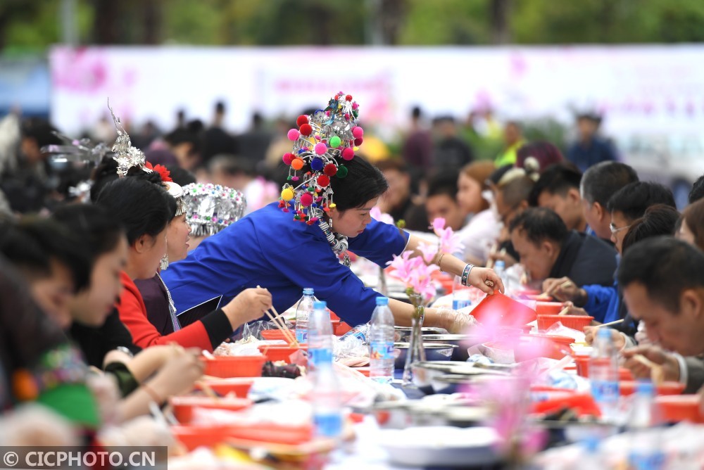 在广西柳州市体育中心,食客在螺蛳粉长桌宴上品尝螺蛳粉及螺蛳美食