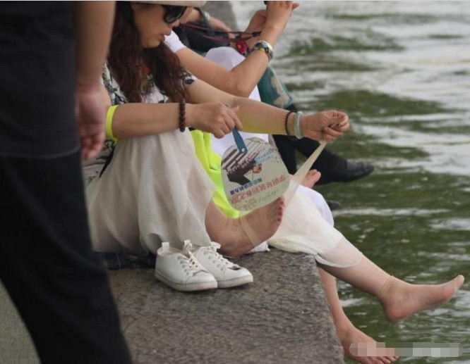 女子西湖边脱鞋洗脚,被保安当场制止,网友们对此事却褒贬不一