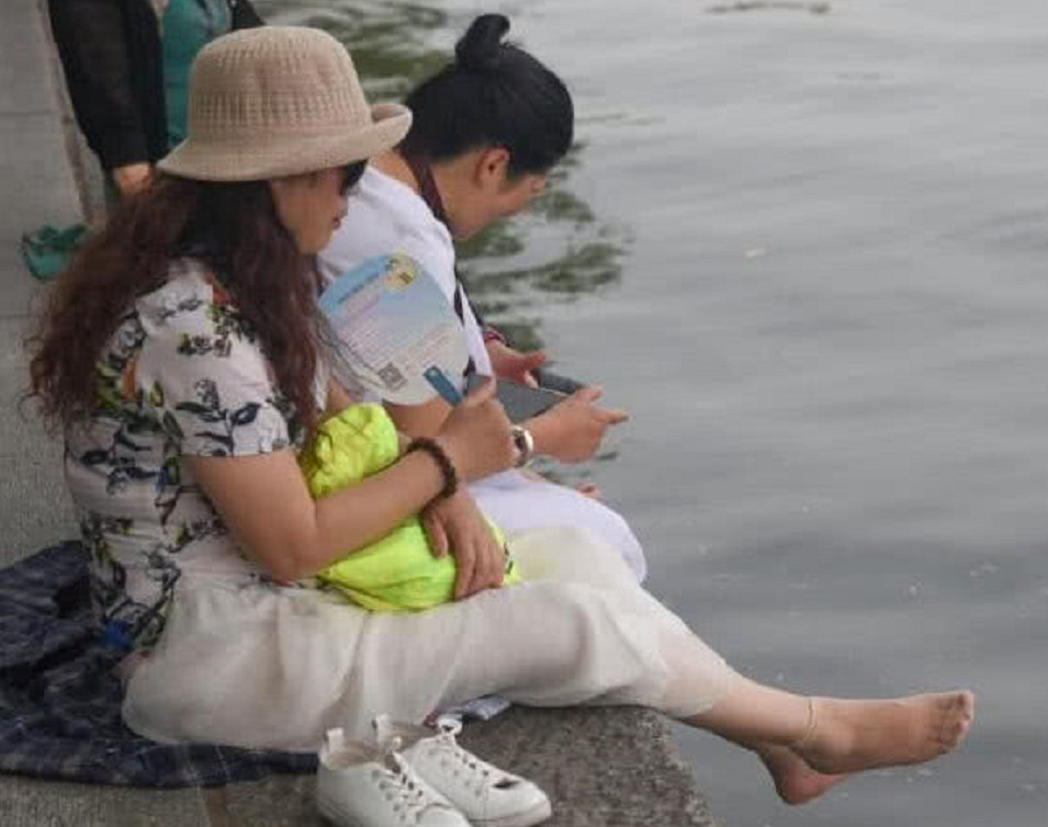 杭州西湖现"脱袜子大妈",在湖里洗脚被保安制止,网友