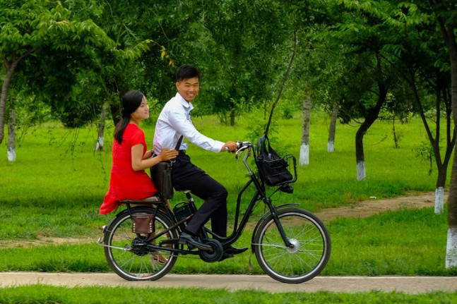 图为朝鲜平壤街头的一对情侣,男生骑着自行车,女生坐在后座上.