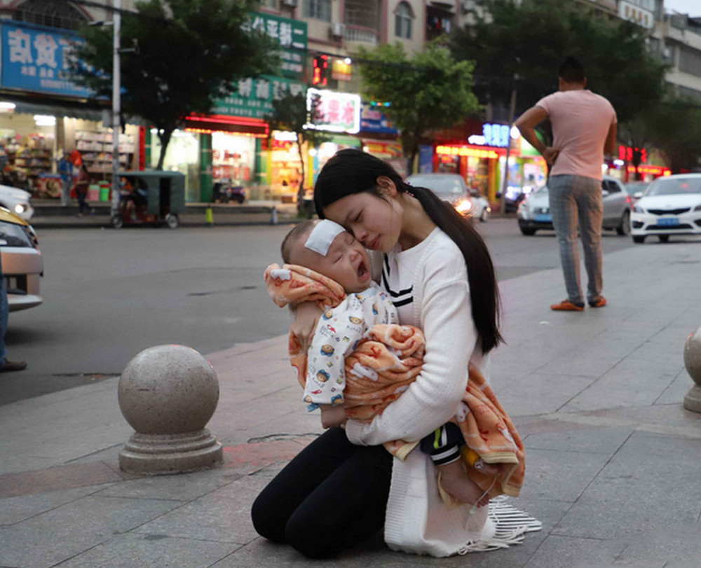 19岁的年轻妈妈,忍着路人投来的异样目光,抱着孩子跪在街头