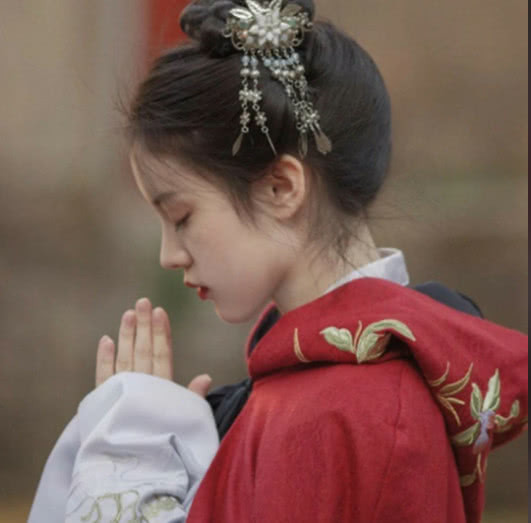 小姐姐穿了一件大红色的长袍,上一张是小姐姐双手合十,好像是在祈祷