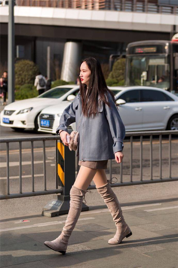 小姐姐长款外套盖着短裙,再搭配一双驼色长筒靴子,显得特别时尚干练