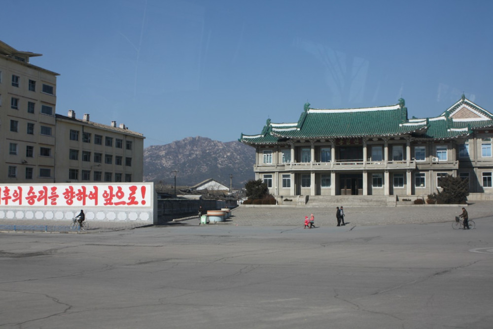 图为朝鲜开城街头的古老建筑,一名朝鲜小男孩在路上张望.