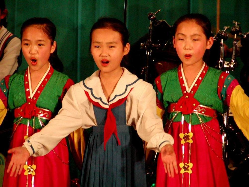图为三名为游客唱歌的朝鲜小女孩,表情有点夸张.