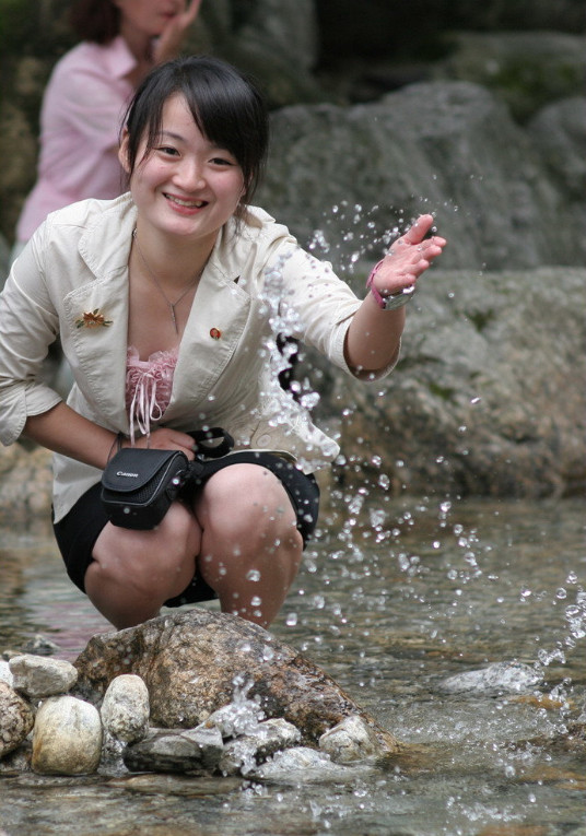 图为一名朝鲜女导游,正在蹲在河边玩水,颜值一般.
