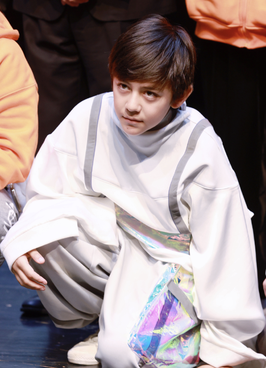 诺一发量浓密,发型乖巧,他蹲在地上,一只手架在膝盖上,眼神深邃,姿势