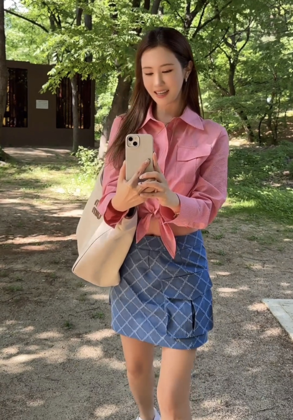 照片中的李多海身穿粉色格子衬衫,搭配牛仔口袋格子迷你裙,展现出清纯