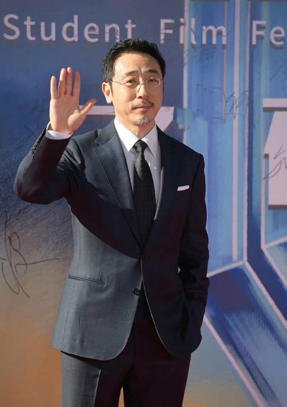 一身黑色西装,搭配白色衬衣,戴着金框眼镜,明明脸上的皱纹和白了的