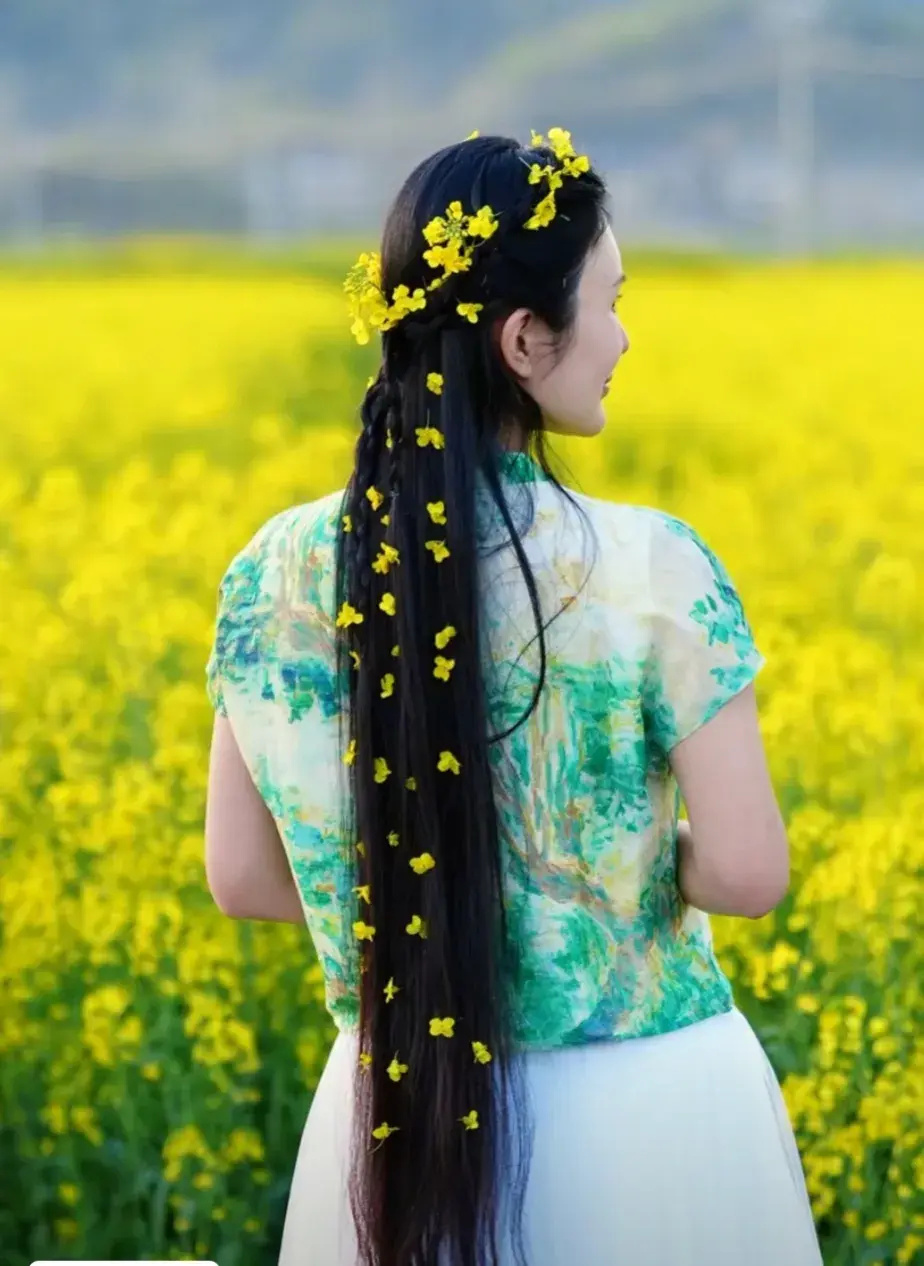 照片中的杜星霖头发上装饰着漂亮的油菜花,面对镜头浅浅微笑,头发又黑