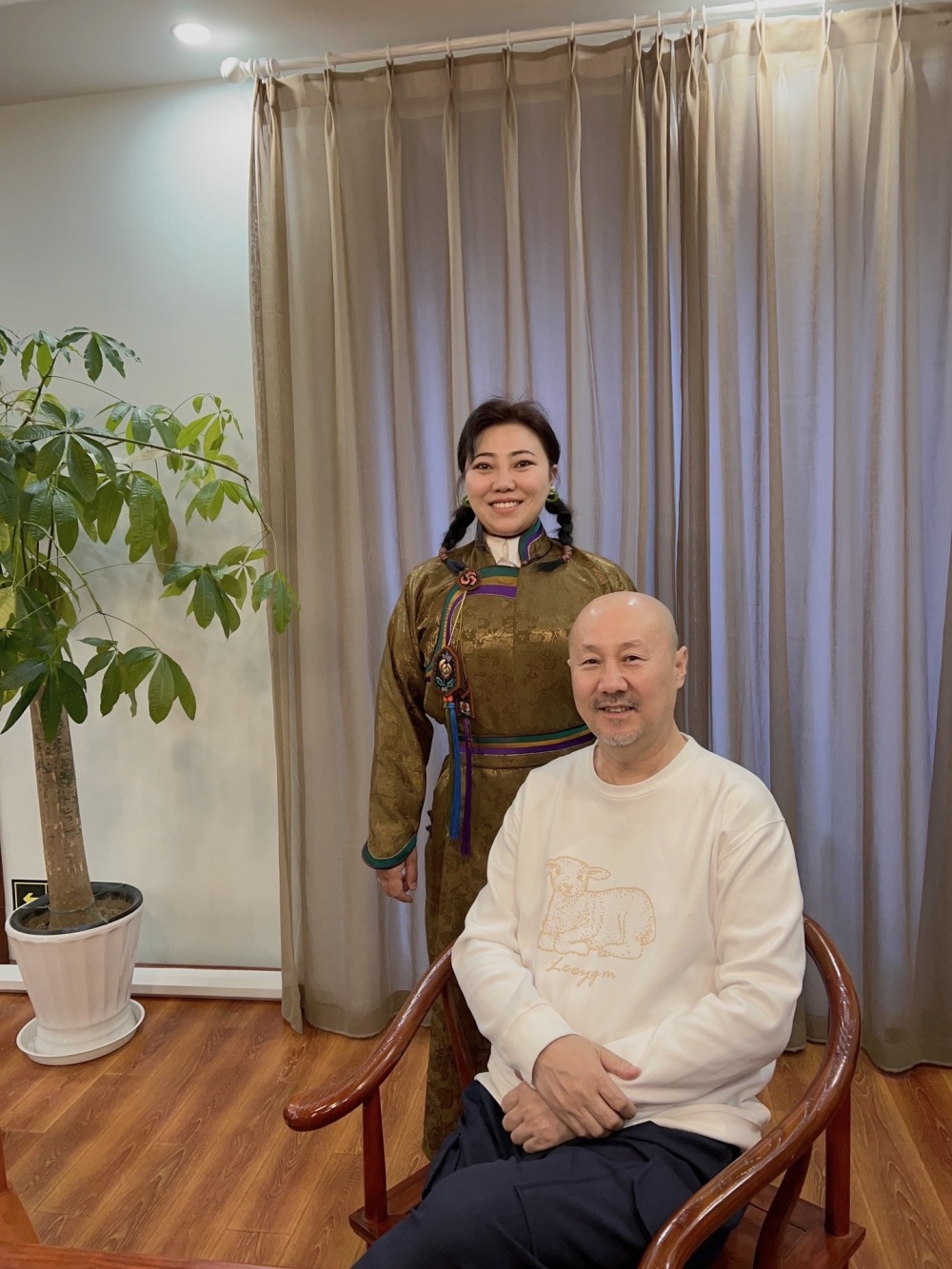 在与孟根花合影时,腾格尔端正的坐在椅子上,双手放在面前,保持着微笑