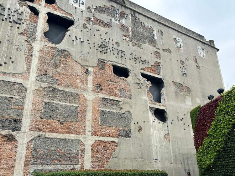 站在四行仓库的弹孔墙前