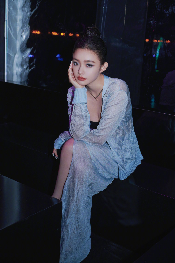 林允翘着二郎腿凹造型,她时而将双手放在膝盖上甜笑,时而又单手托腮摆