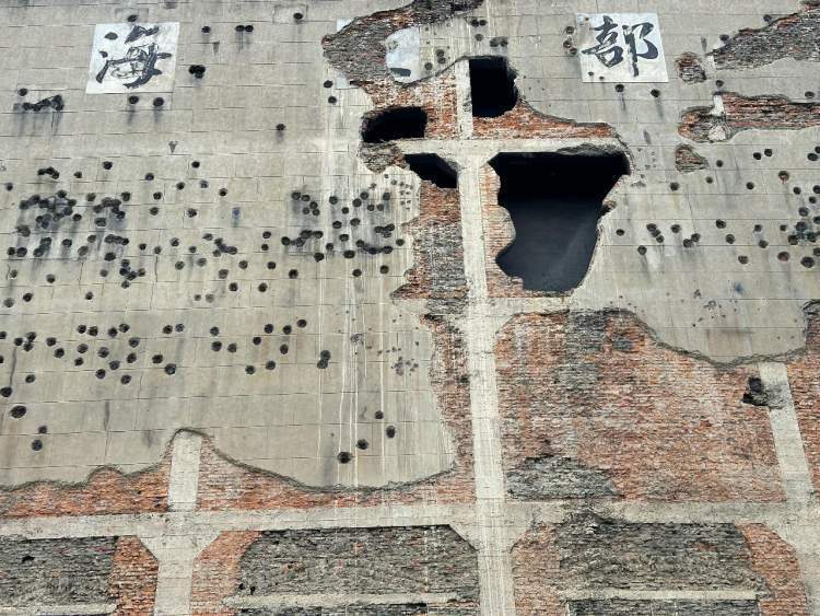 站在四行仓库的弹孔墙前