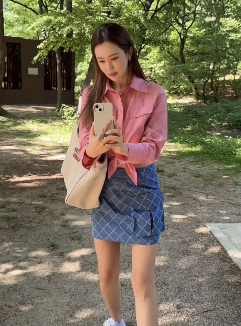 照片中的李多海身穿粉色格子衬衫,搭配牛仔口袋格子迷你裙,展现出清纯