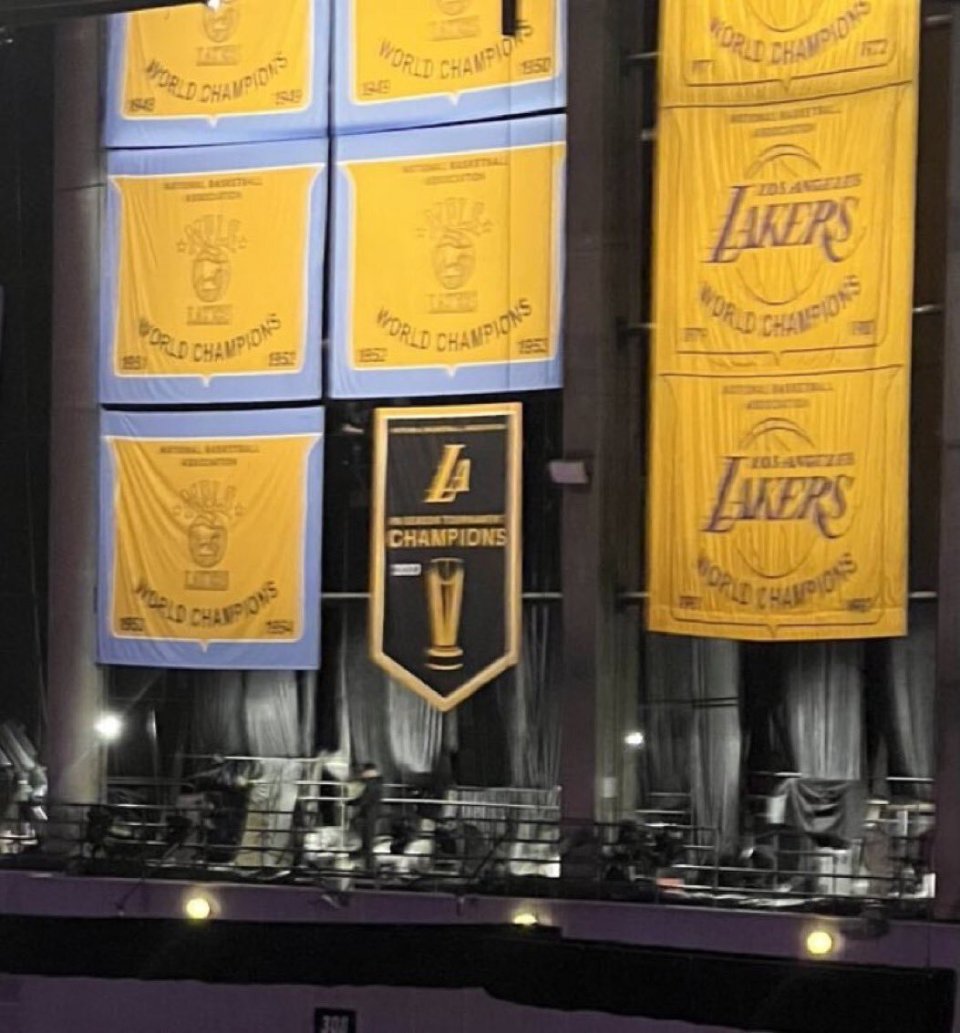 上面印着湖人标志la和季中赛冠军奖杯以及冠军字样;湖人总冠军旗帜则