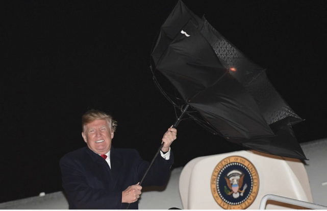 也有不吹头发改吹伞的。图为特朗普的伞在风中被吹了个“里朝外”，虽然竭尽全力“搏斗”，特朗普终究还是没有能够赢了风。 (来自:什么值得看)