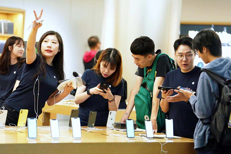 店员为顾客介绍新款iphone手机的功能.