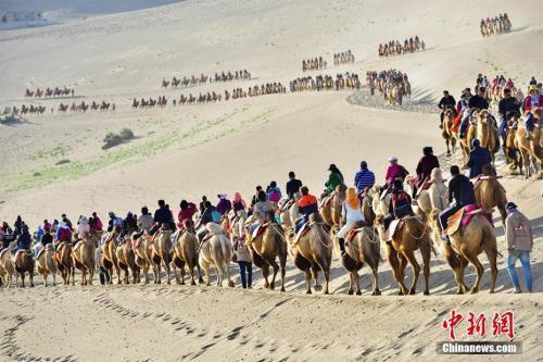 国庆长假期间，国际旅游名城甘肃敦煌著名景区鸣沙山月牙泉旅游迎来“高峰模式”。据统计，10月3日，该景区接待中外游客达到3万人次，掀起金秋敦煌旅游新高潮。王斌银 摄