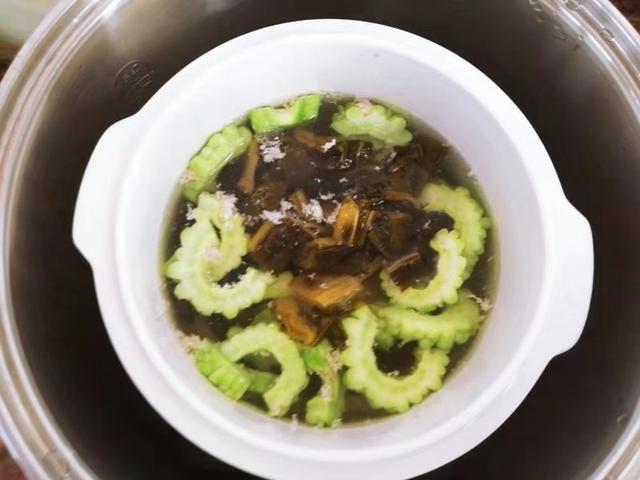 5,一个小时后,打开锅盖,把切好的苦瓜和酸菜都放进去,搅拌开来,再炖