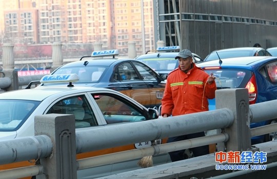 车流中的清洁工。 中新经纬摄