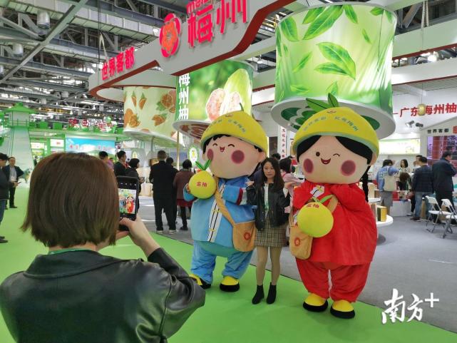 "来自陕西,甘肃的参会嘉宾到梅州展区找梅州柚吉祥物"客客"都都"合影
