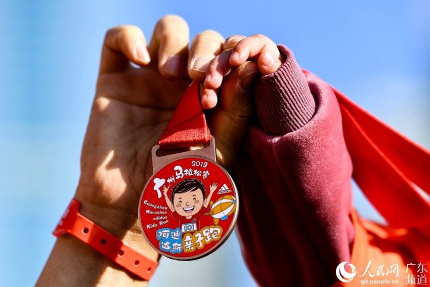 家长和小孩展示纪念奖牌. 主办方供图