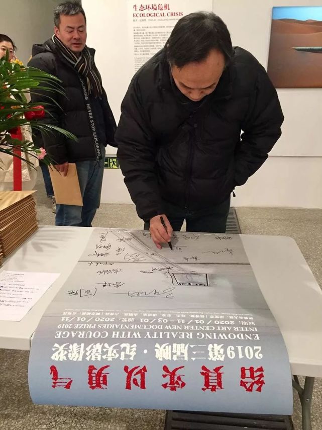 摄影批评家鲍昆在海报上签名留念映画廊之友基金会代表谢树峰在海报上