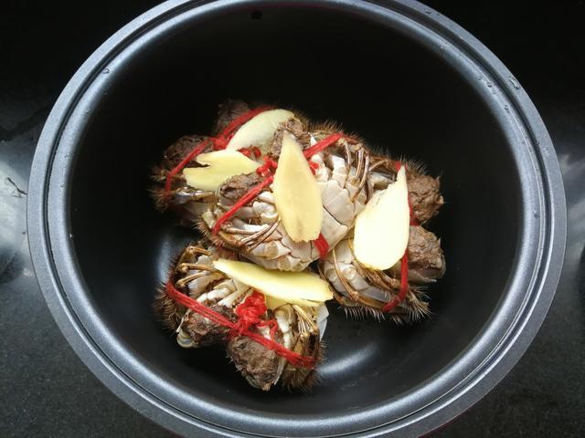 将螃蟹肚子朝上放电饭煲专用的蒸屉上,并在螃蟹身上摆上切好的生姜片