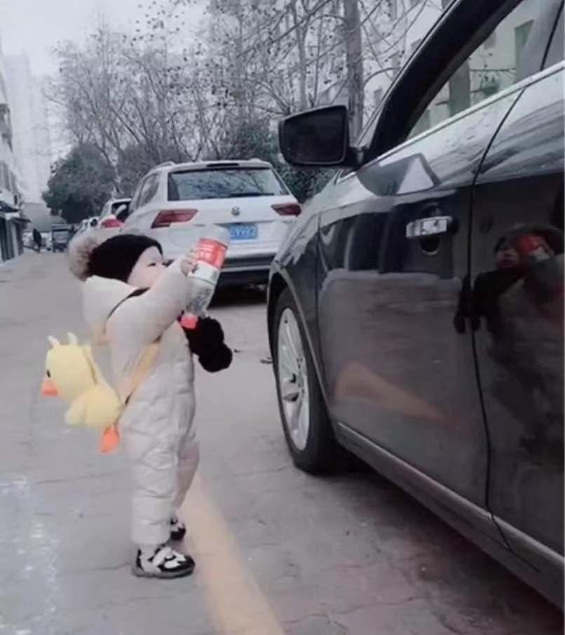 师傅顺手将一个饮料瓶扔出了窗外,这位小朋友穿着一身白色的棉衣棉裤