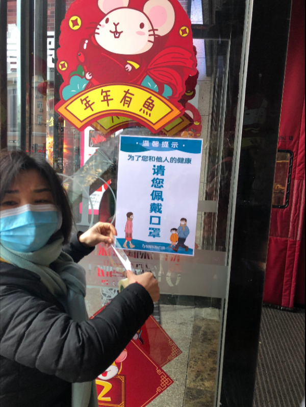 有戴口罩工作人员在贴温馨提示商场内静悄悄昨天回家时,还发现有路人