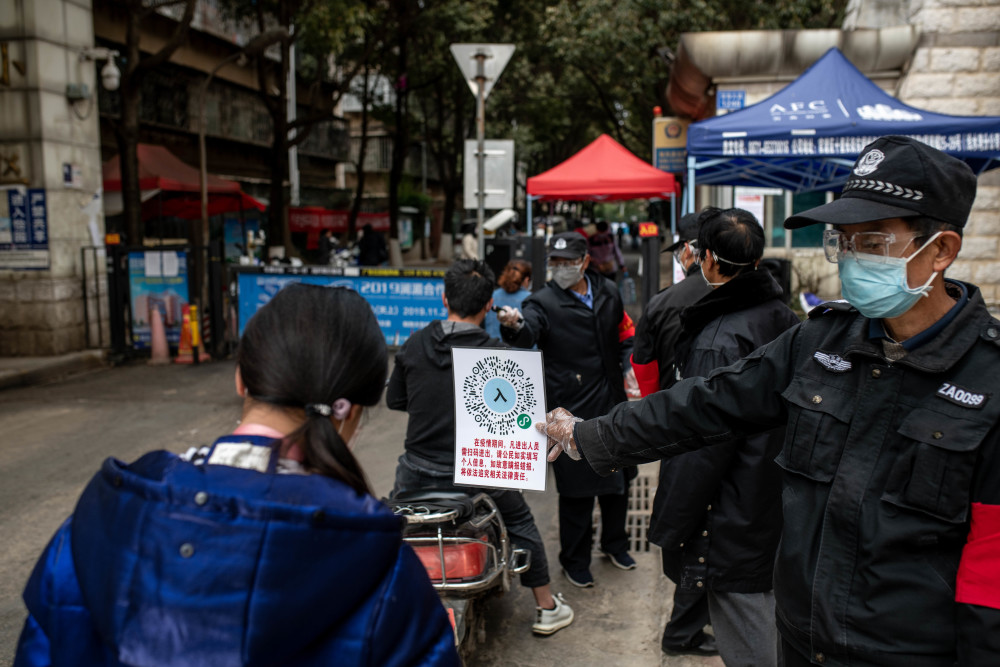 2月15日,在云南省昆明市怡园小区门口,工作人员引导市民扫码出入小区.