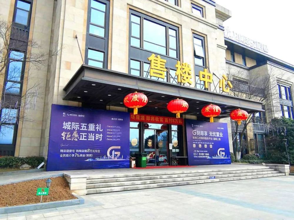 售楼处门口正摆放着"精装健康宅,购精装赠8万元车位"的桁架.