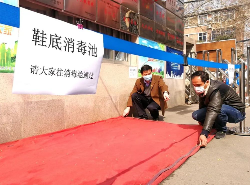 工作人员在学校大门口西侧以及食堂门口搭建了一个简易的鞋底消毒池